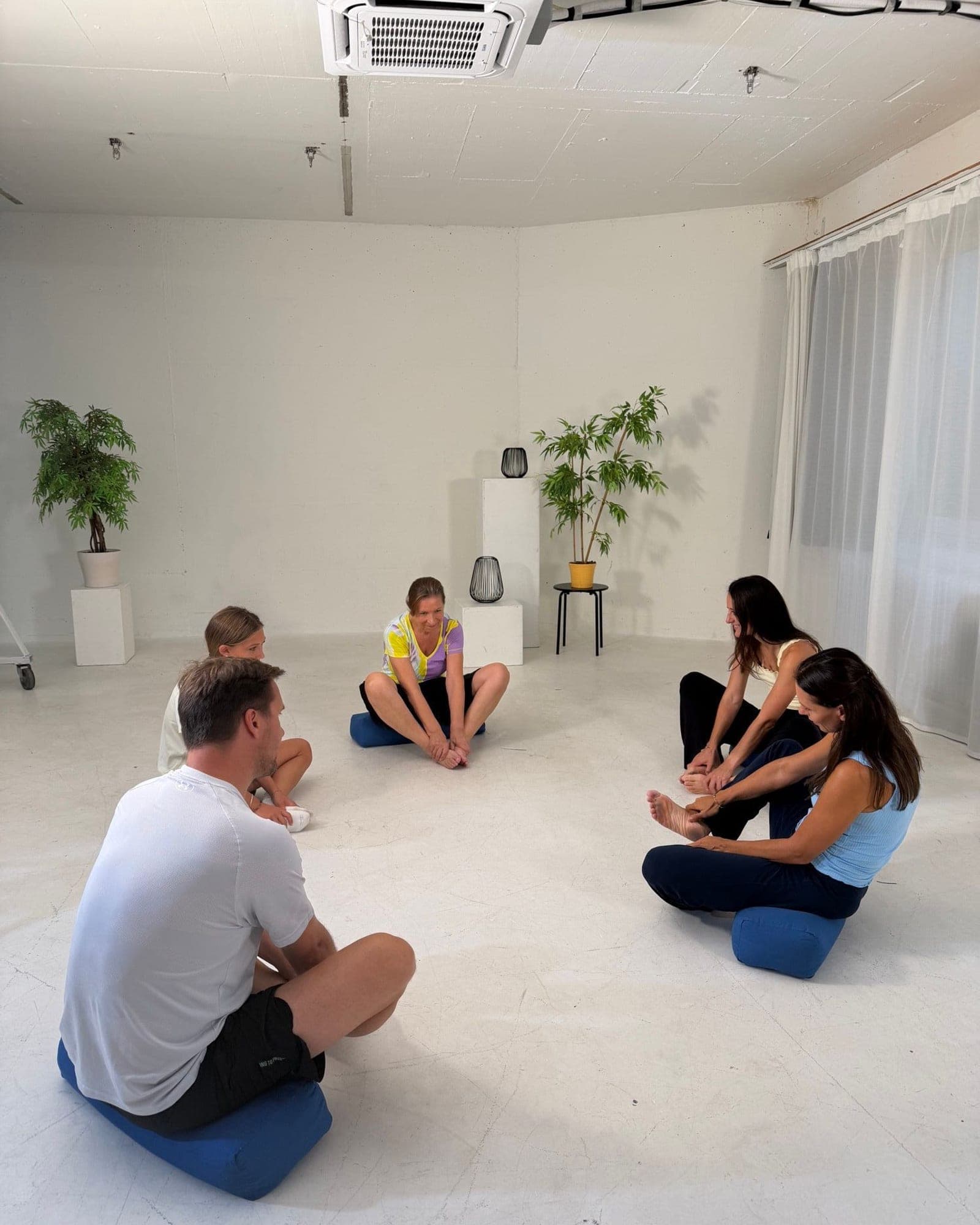 Workshop group sitting in a circle on cushions, working on their feet